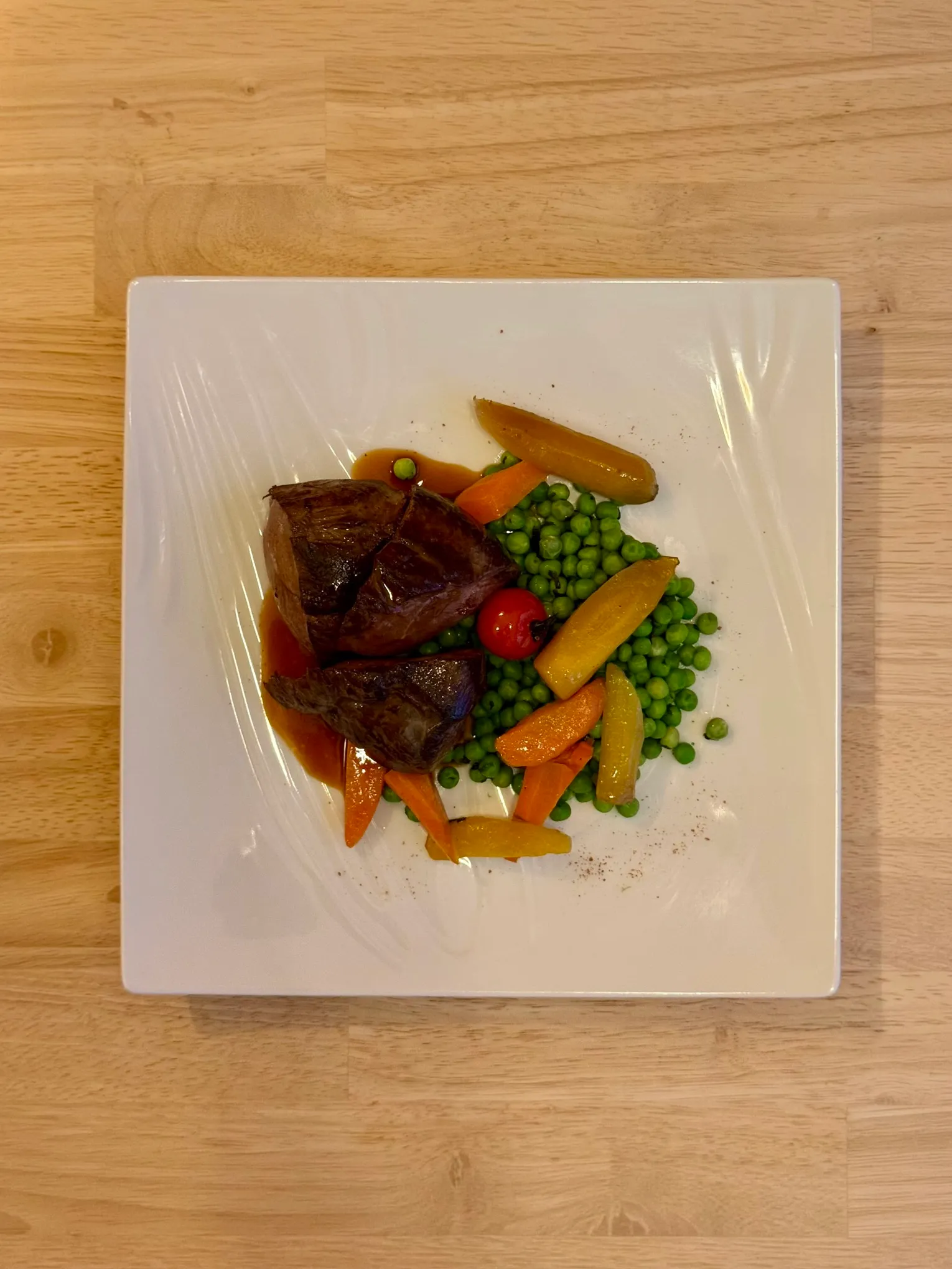 Pièce de bœuf en sauce, petits pois et carottes fanes glacées