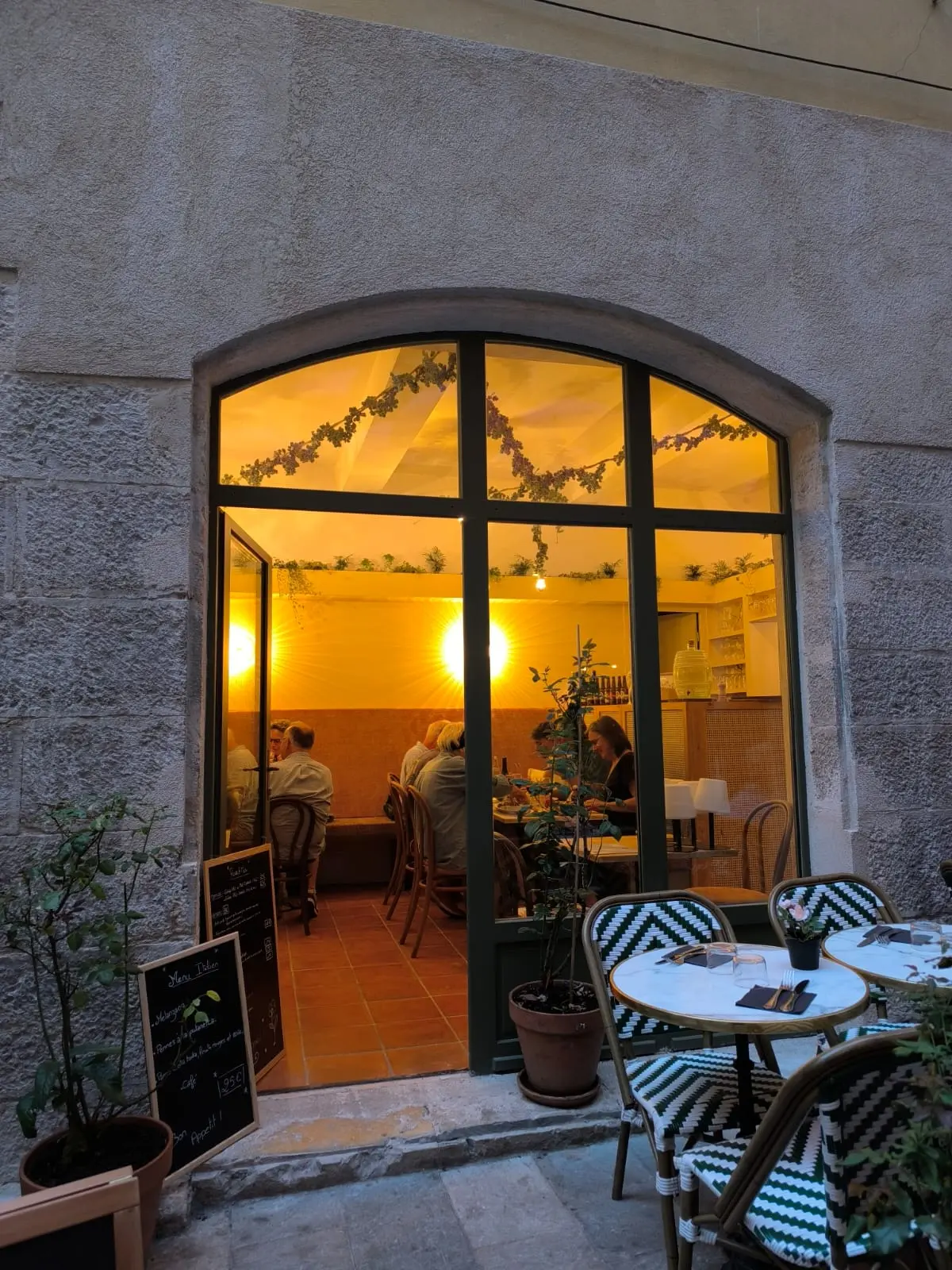 Devanture du restaurant Roses & Mets le soir avec terrasse illuminée