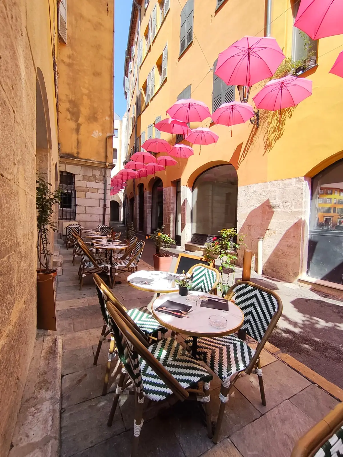 Terrasse du restaurant Roses & Mets avec parasols roses dans le centre de Grasse